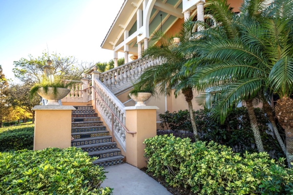 A staircase with a stone railing and tiles against the back of each step, surrounded by tropical landscaping.