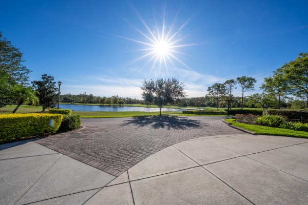 An expanse of gray pavement with trees and a small lake in the distance. 