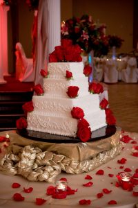 White 4 tier wedding cake with red roses going up corner of each tier