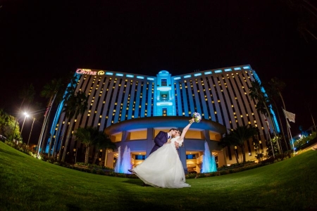 A bride and groom kiss on the front lawn of Rosen Centre at night, with the hotel and fountains lit up behind them. Rosen Centre is a beautiful destination for a hotel wedding.