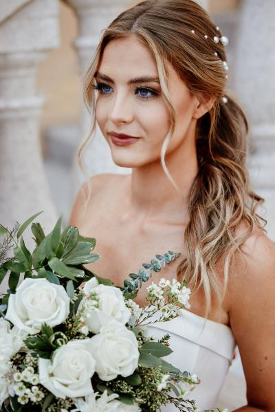 A beautiful bride with a side pony tail holding a bouquet of flowers at Rosen Shingle Creek. 