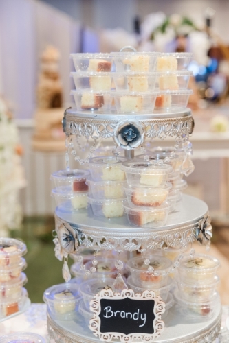 Bite-sized wedding cake samples on a silver three-tiered tray at a wedding expo.