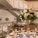 A beautiful two-story ballroom with a staircase set up for a formal wedding event.