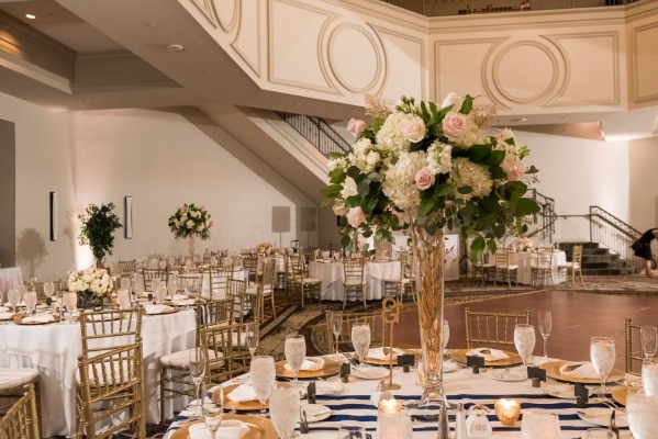 A beautiful two-story ballroom with a staircase set up for a formal wedding event.