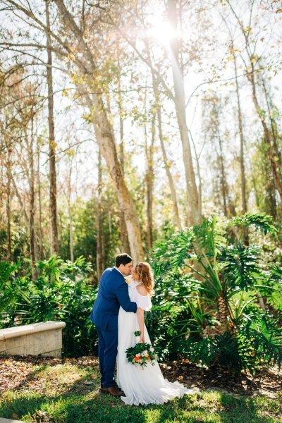 A bride and groom stand amidst beautiful greenery at Rosen Plaza.