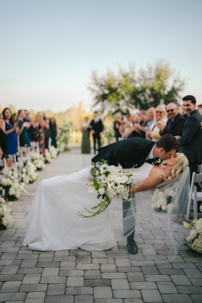 A bride and groom kiss at the end of an outdoor wedding aisle at Rosen Shingle Creek.