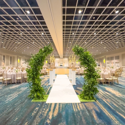 Two arches adorned with greenery in between the aisle of an indoor wedding ceremony venue in Orlando.