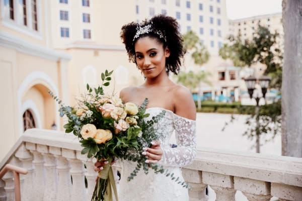 A bride holding a wedding bouquet of light orange flowers.