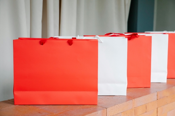 A row of alternating red and white gift bags on a stone surface.