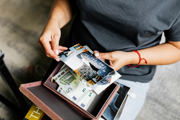 A close-up of a woman’s hands holding photographs over a box of mementos.  