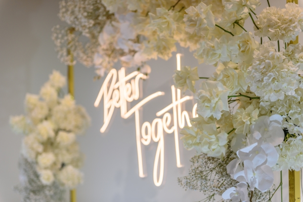A neon sign reading 'Better Together' framed by a white floral archway, perfect for a social-forward wedding.