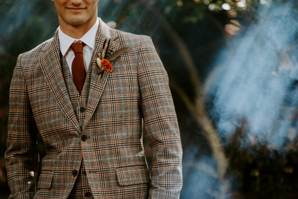 The torso of a man in a plaid suit with a red tie. 