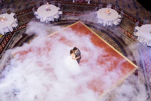 A newlywed couple sharing a dance inside a stunning wedding reception room.