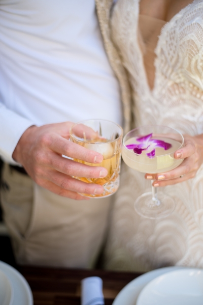 A close-up of a bride and groom holding two distinct signature wedding cocktails.