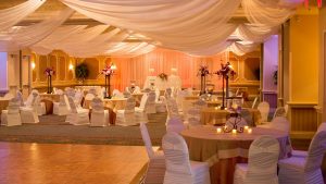 Wedding Reception Tables with White Chairs and Beige Table Cloth