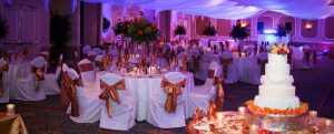 White chairs with orange bows, white table cloths, 4 tier cake with orange flowers