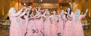Indian women weaing pink gowns throwing flower petals in air