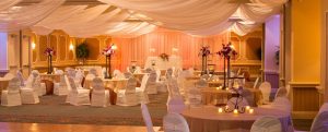 Wedding reception with orange ambient light, white chairs, at Rosen Plaza