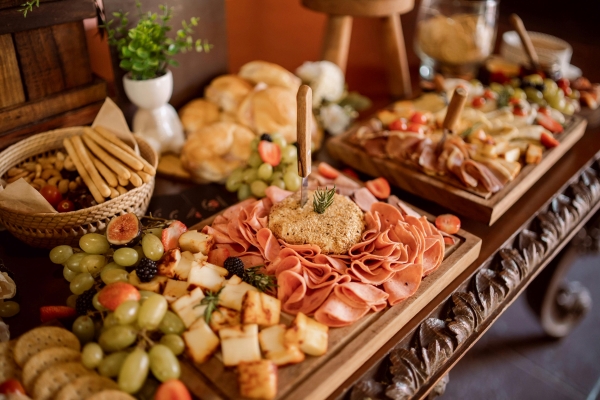 A close-up of a charcuterie display with meats, cheeses, and breadsticks on an ornate wooden table.