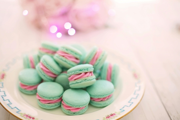 A plate of tiffany blue macarons with bright pink filling on a vintage floral plate. 