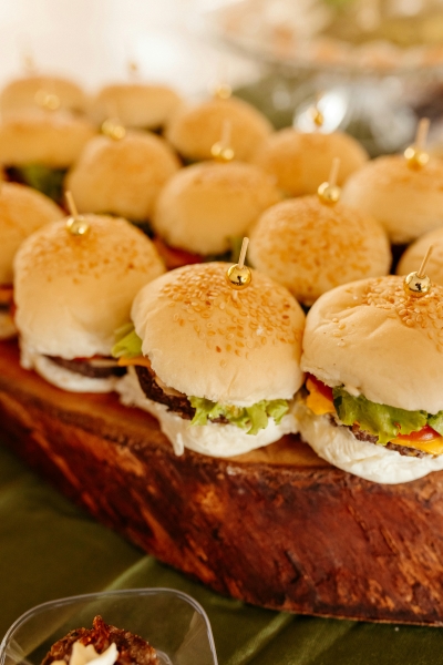 A closeup of slider burgers on a wooden serving tray.