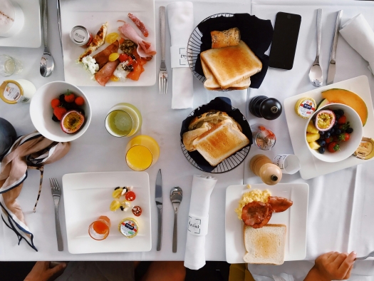 An aerial view of a table set with breakfast items like toast, orange juice, bowls of fresh fruit, and more. A post-wedding brunch continues the celebrations beyond your wedding day.