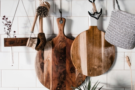 Two round wooden cutting boards hang against a white tile wall with other accessories. When building a wedding registry, keep it updated so guests don't run out of options.