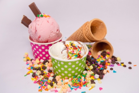 Ice cream scoops in cups surrounded by cones and colorful toppings. An ice cream truck is a great wedding dessert alternative.