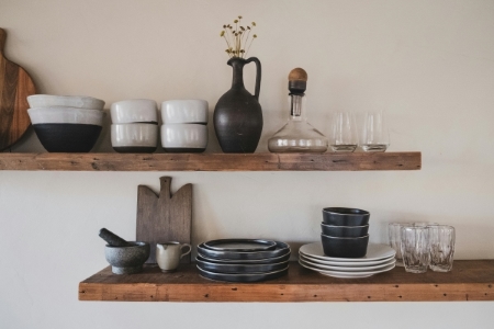 Two wooden shelves with bowls, plates, glasses, cutting boards, and a vase. Building a great wedding registry includes finding a balance of everyday items and heirloom pieces to be treasured.