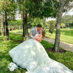 A bride dressed in a white gown and groom dressed in a grey suit kissing outdoors at Rosen Plaza, a beautiful wedding venue to host your big day.