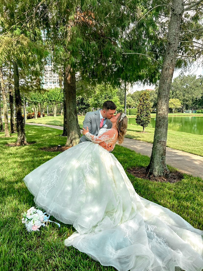 A bride dressed in a white gown and groom dressed in a grey suit kissing outdoors at Rosen Plaza, a beautiful wedding venue to host your big day. 