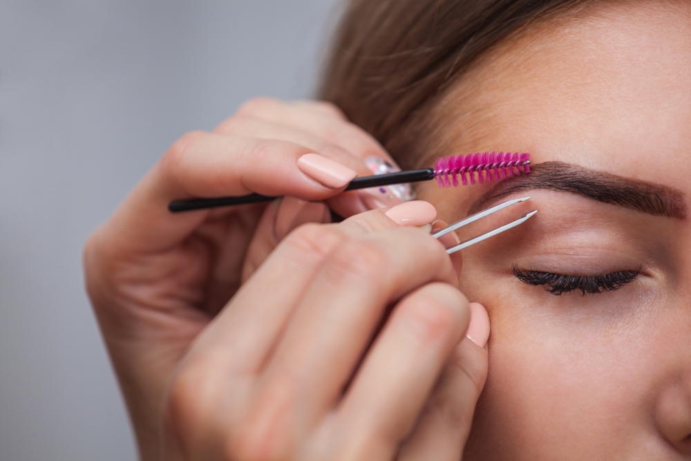 A close-up of a woman having her eyebrows tweezed and plucked. 